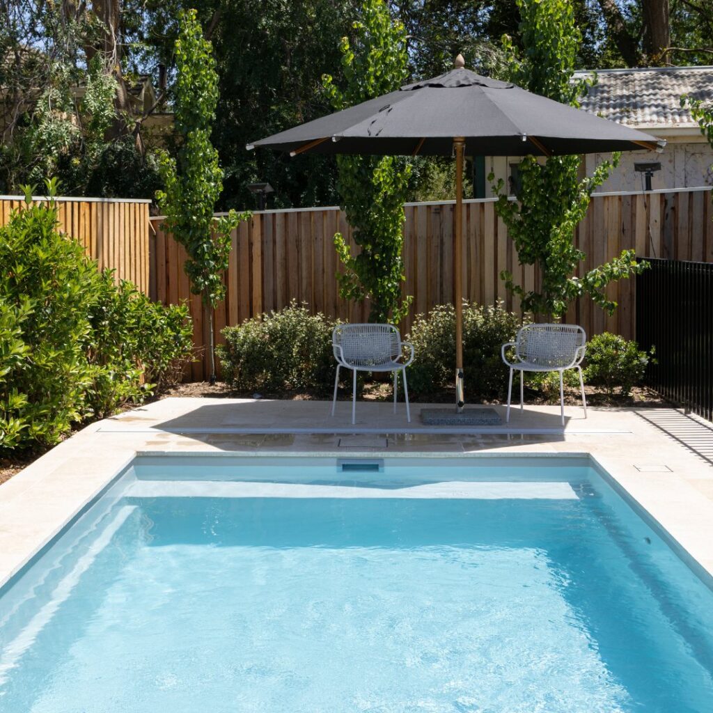 Rectangular pool with a timber fence and an outdoor umbrella in a Canberra backyard