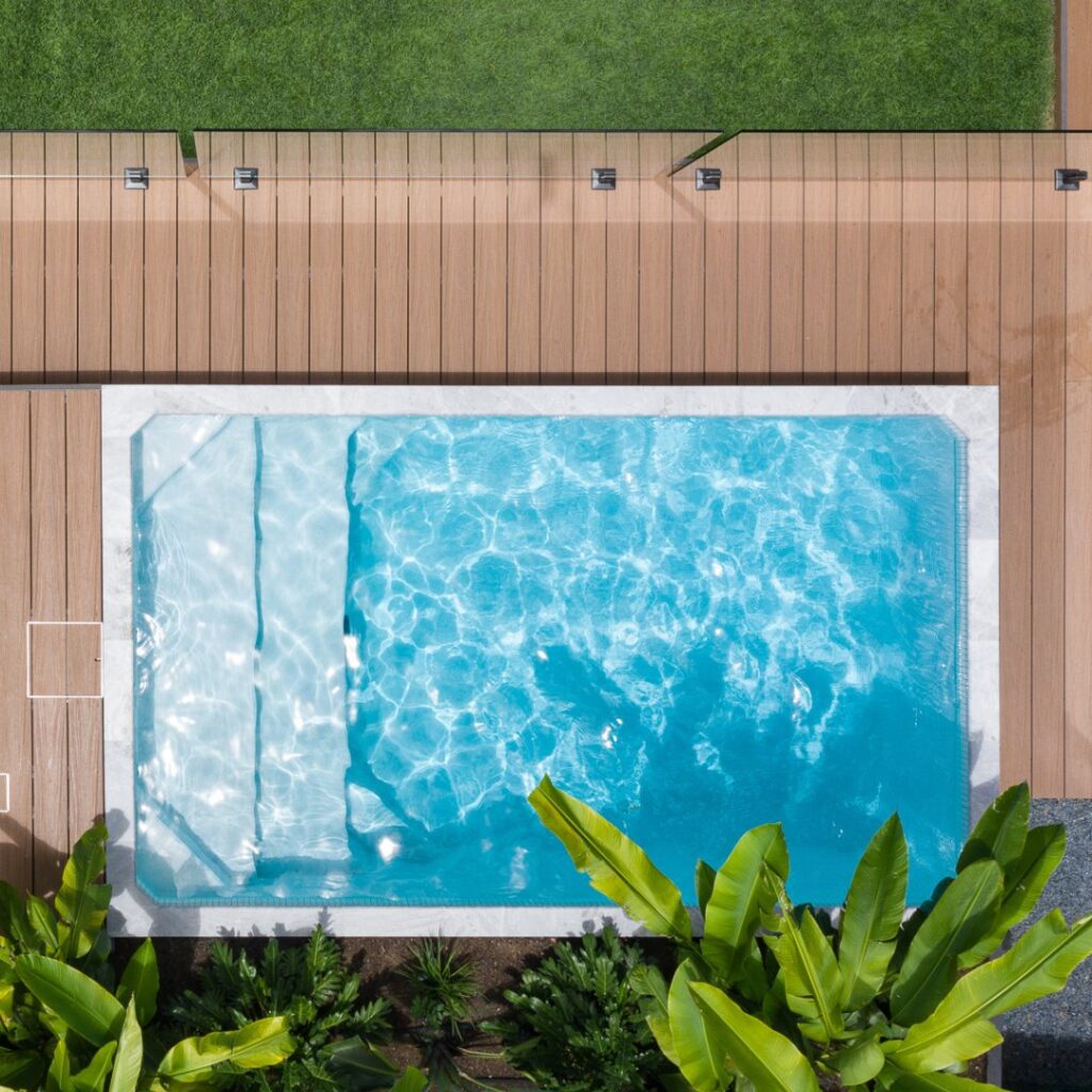 Aerial view of a pool and deck in a landscaped backyard