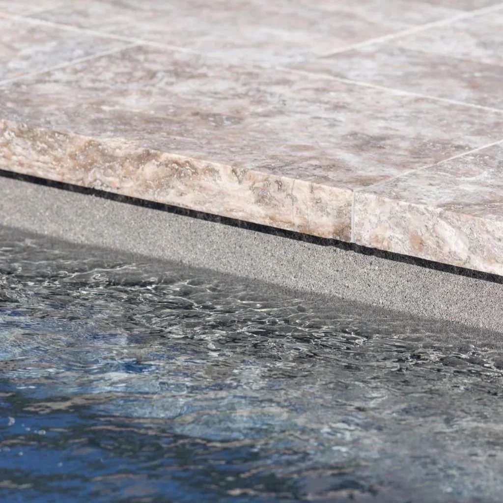 Close up of travertine pool coping at the waterline