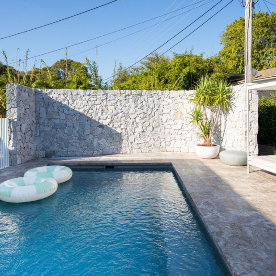 Pool set against a stone feature wall with floats on the water